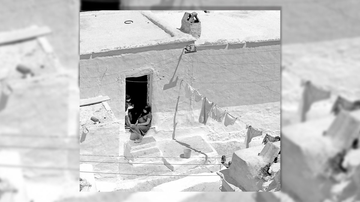 Una muchacha embarazada sentada en el tranco de la puerta en una casa en los cerros de La Chanca.