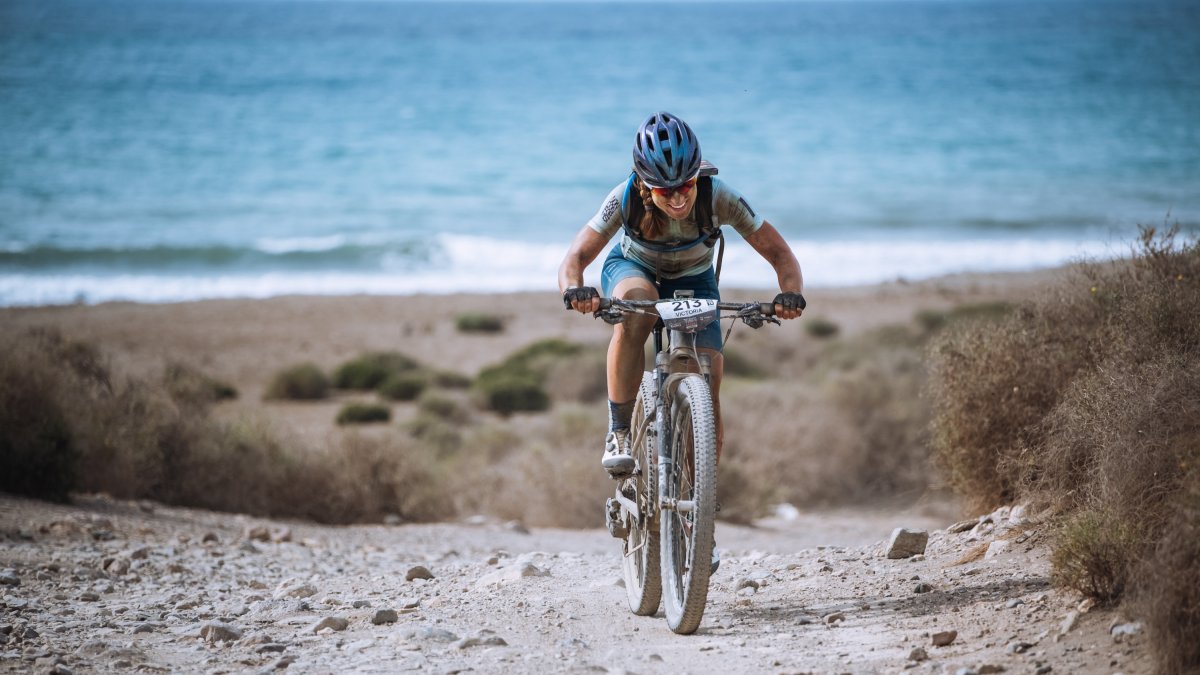 Una corredora asciende con el Mediterráneo de fondo durante una de las pruebas de la Škoda Titan Desert Almería.