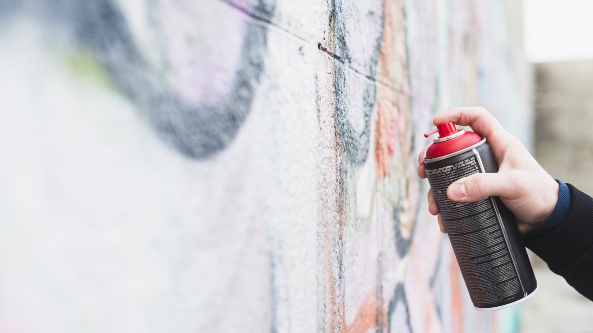 Una persona pintando una pared con aerosol.