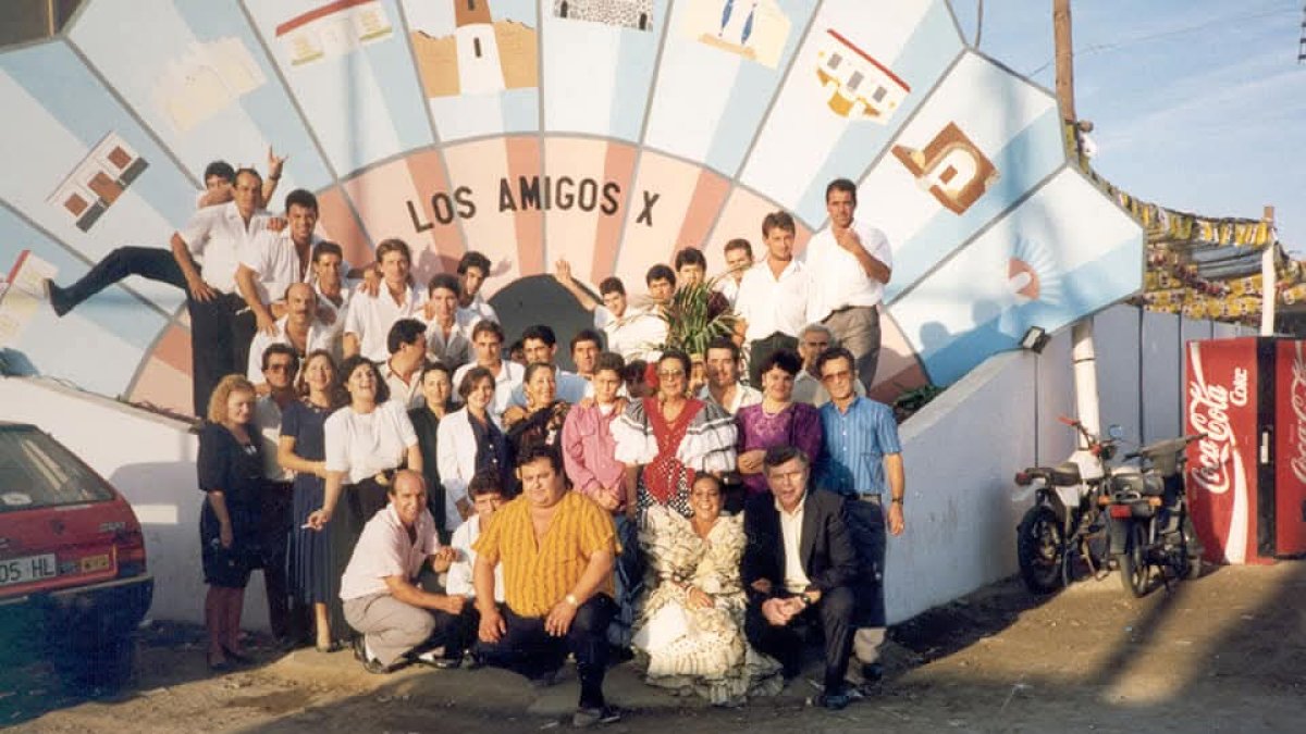 En su décimo Aniversario socios y camareros junto a la portada de la caseta.