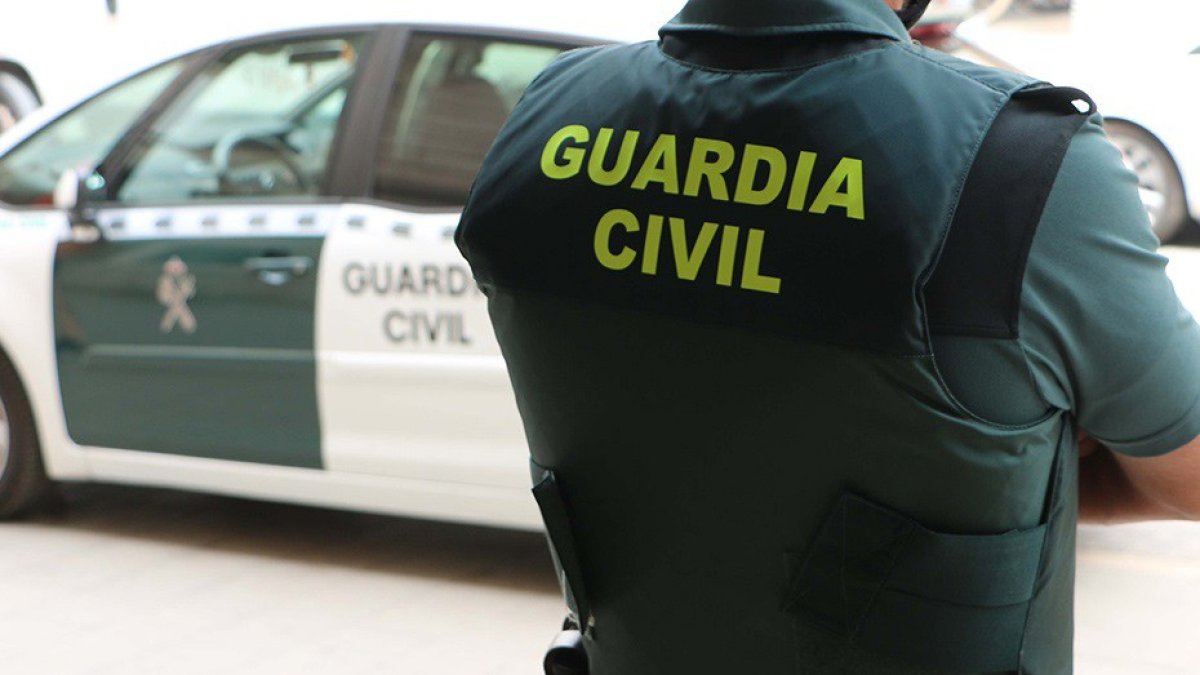 Archivo - Un agente de la Guardia Civil, de espaldas, junto a un vehículo oficial.