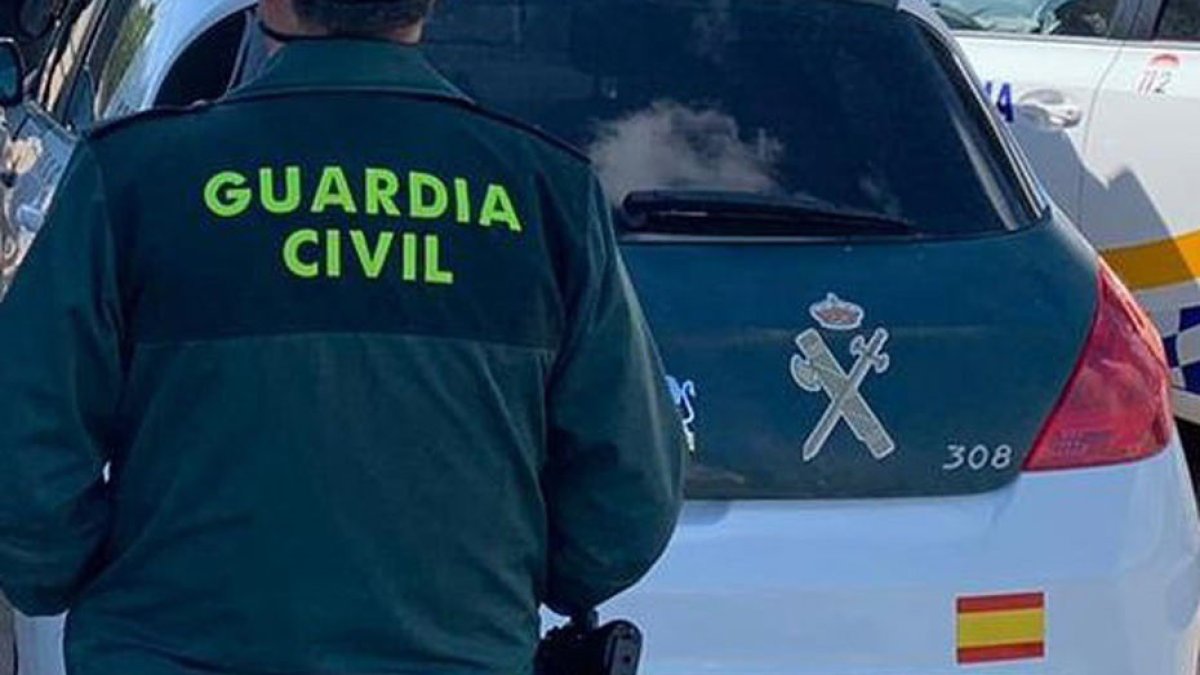 Archivo - Imagen de archivo de un agente de la Guardia Civil junto a un vehículo oficial.