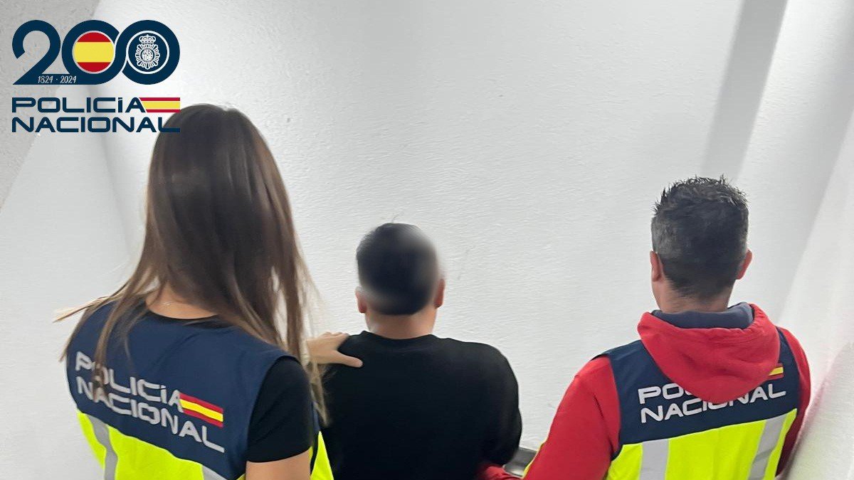 El detenido, de espaldas, custodiado por dos agentes de la Policía Nacional.