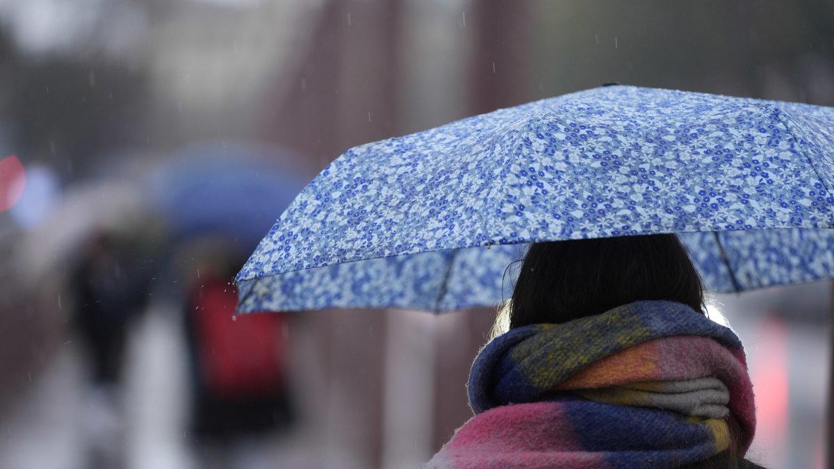 Archivo - Una persona se protege de la lluvia con un paraguas.
