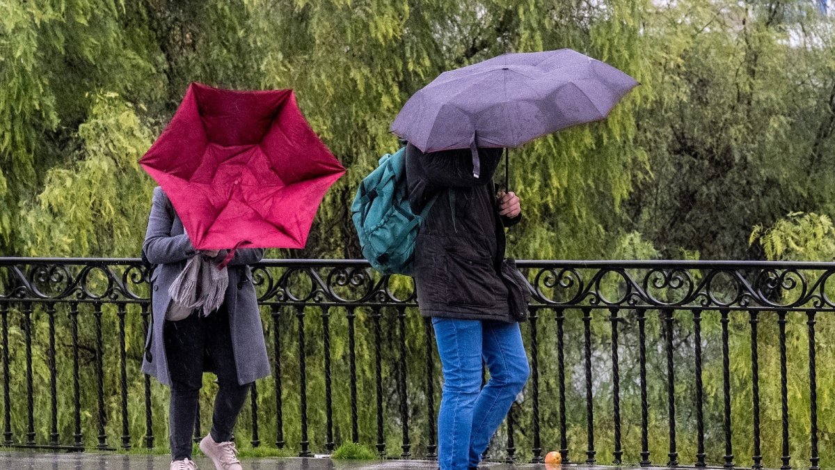 Imagen de dos ciudadanos en un día de lluvia y fuerte viento.