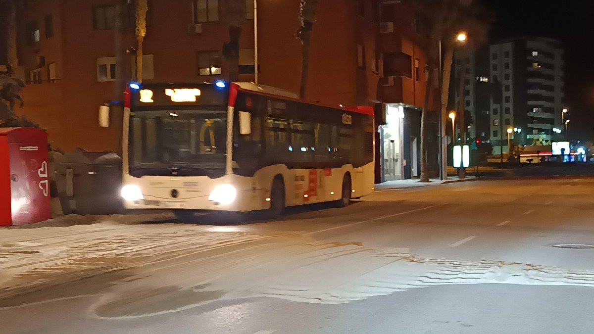 Un autobús del transporte público urbano de la capital pasando a baja velocidad sobre la acumulación de arena.
