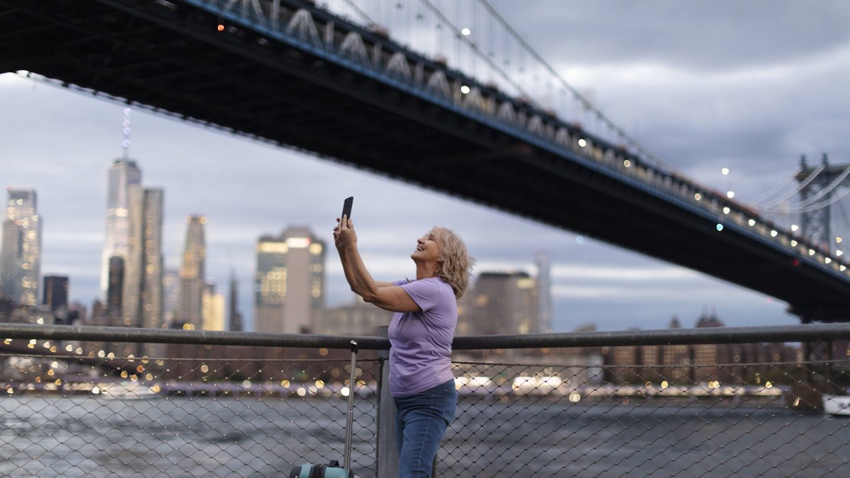 Una viajera inmortaliza el skyline de Nueva York al atardecer, bajo el puente de Brooklyn.