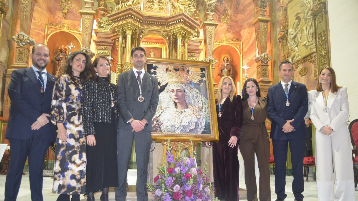 El Pregonero y la Hermana Mayor del Paso Blanco junto al equipo de gobierno posan junto al Cartel de Semana Santa 2026