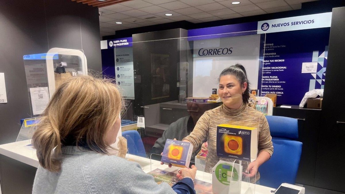 Una trabajadora de Correos muestra una baliza V16 homologada por la DGT en una oficina de la provincia de Almería.