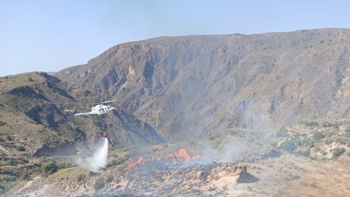 Un helicóptero del Plan Infoca realiza una descarga de agua durante los trabajos de extinción del incendio forestal declarado en Berja (Almería).