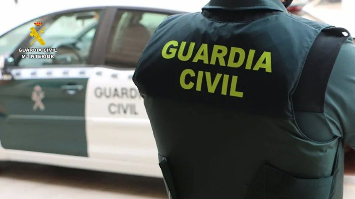 Archivo - Un agente de la Guardia Civil junto a un vehículo oficial.