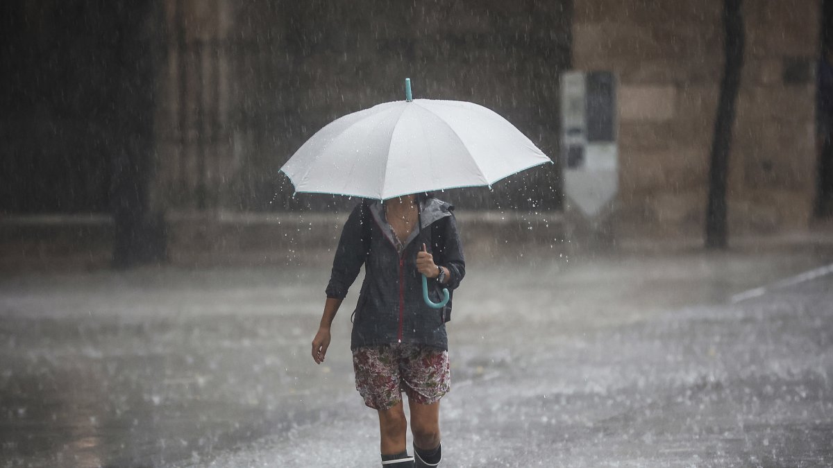 Una mujer camina bajo un paraguas en una jornada de lluvia.