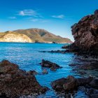 Las rocas de origen volcánico emergen del agua azul en la Playa Negra