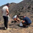 Un agente de la Guardia Civil, recogiendo restos óseos un mes y medio después del incendio en presencia del hijo de una de las víctimas y el alcalde de Bédar.