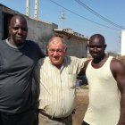 El pastor Antonio Cara se abraza a dos inquilinos de su vivienda: Mamadou y Ansumana.