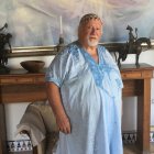 Manolo Coronado con su túnica azul, bajo uno de sus cuadros, en su casa de la montaña.