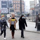 Tres jóvenes caminan por Milán, dos de ellas con mascarillas.
