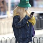 Una mujer con una mascarilla y un teléfono en mano.