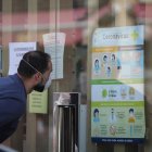 Un hombre consulta recomendaciones en el escaparate de un establecimiento.