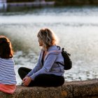 Una madre con su hija sentada a la orilla del río Guadalquivir con el barrio de Triana al fondo.