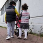 Dos niños pasean por la calle con mascarillas.