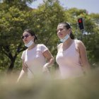Dos mujeres caminan con la mascarilla bajada.