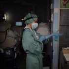 Una sanitaria se pone unos guantes en la Unidad de Cuidados Intensivos.