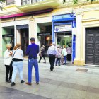 Varias personas en la cola de una administración para comprar un décimo del Sorteo de Navidad.