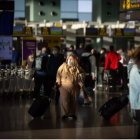 Varios pasajeros con maletas en el aeropuerto de El Prat, en Barcelona.