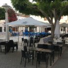 Imagen de la plaza de Agua Amarga, ocupada por mesas y sillas, desde primera hora de la mañana.