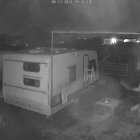 Uno de los ladrones tira maderos al perro del dueño de la casa, captado por una cámara de vigilancia.