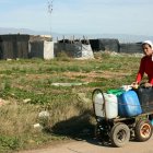 Una mujer transporta envases con agua entre chabolas de El Ejido.
