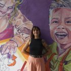 La artista Tati Salvador posa en uno de los murales que ha pintado en la fachada de su centro \'Tu Arte lo Parte\'.
