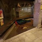 En la puerta del local duerme con su mochila roja.