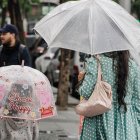 Una mujer y su hija, con un paraguas en un día de lluvia.