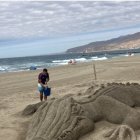 Karim refrescando a su caimán, ya desaparecido,, sobre la arena de la playa de El Zapillo.