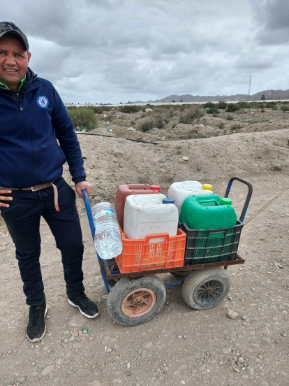 Un hombre tira de su carro improvisado para llenar las garrafas de agua.